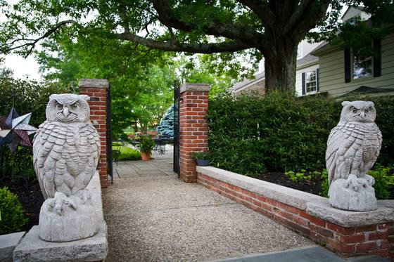 A stone gateway with owl statues, leading into the estate gardens